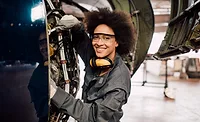smiling woman working on an airplane engine