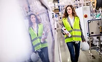 woman in reflective vest carrying binder